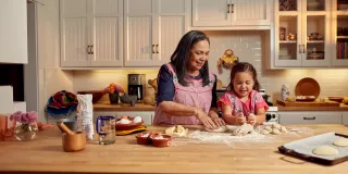 Woman and her grandchild are baking in a kitchen